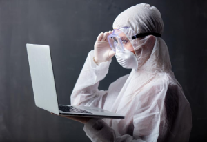 picture of medical person in protective clothing holding laptop